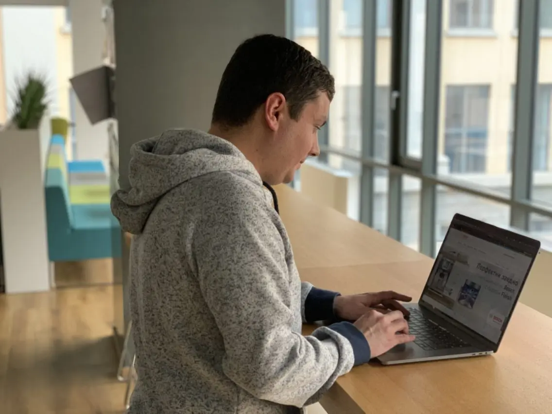 man at a desk in front of a laptop from behind