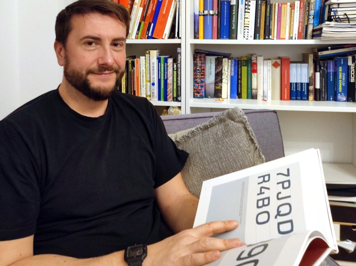 man with book sitting in front of a bookshelf