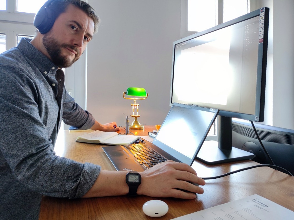 man with headphones standing at a desk in front of a computer