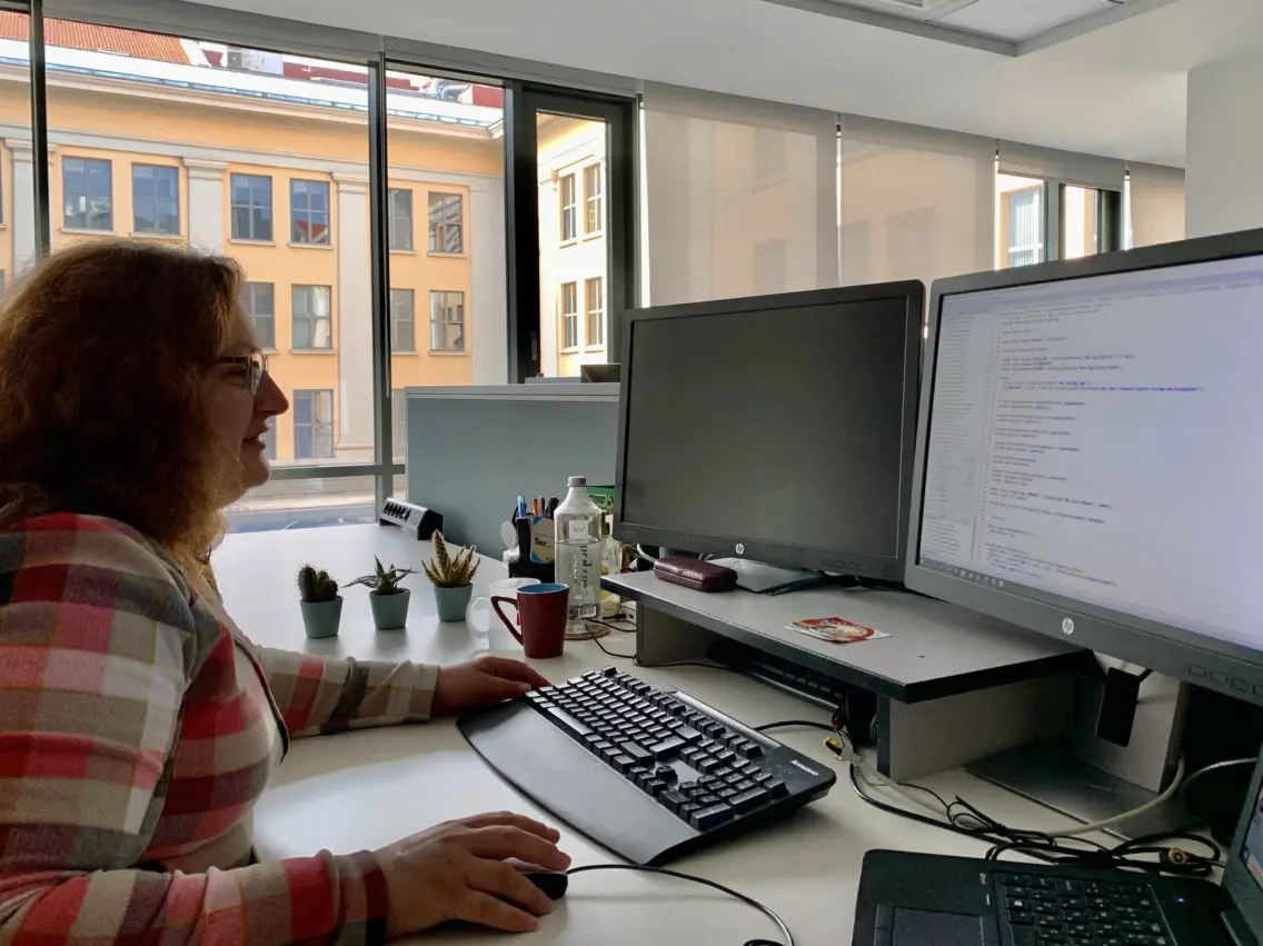 Woman sitting at a desk in front of computer screens